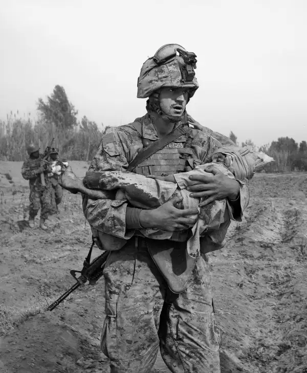 A Marine carries an Afghan child, one of two wounded by coalition aircraft during an air support mission.