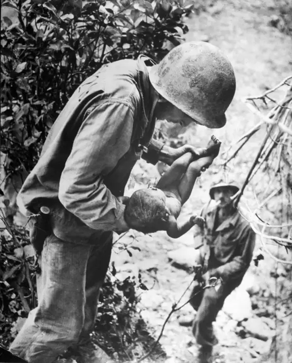 In a W. Eugene Smith photo that, somehow, captures both tenderness and horror, a U.S. Marine cradles a near-dead infant that the Marine found wedged, face down, literally under a rock while clearing out Japanese soldiers hiding in caves on Saipan, in the Mariana Islands. Hundreds of Japanese civilians in the islands committed suicide rather than surrender to the Americans.