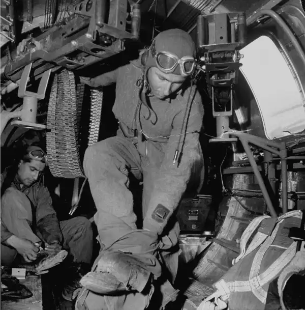 A ball-turret gunner takes off his high-altitude clothing upon return from a sucessful bombing mission at a Sahara desert airdrome in 1943.