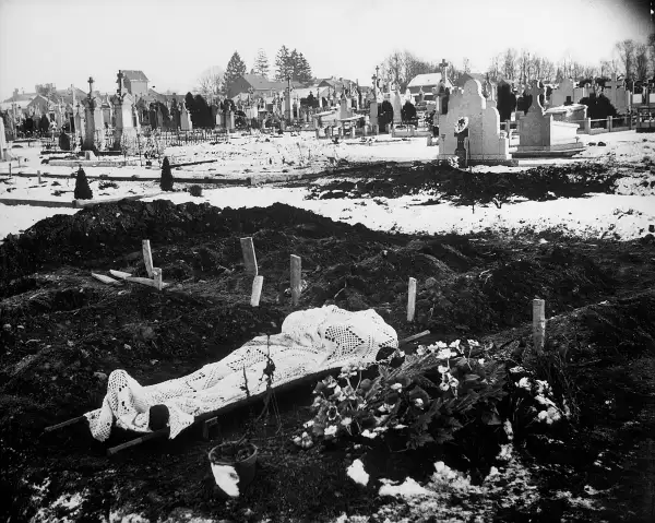 A lace curtain shrouds the body of an American soldier awaiting burial in the Bastogne cemetery.