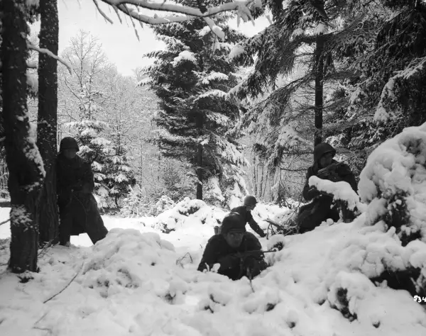 American infrantry from the 290th Regiment crouch in snowy woods near Amonines, Belgium, January 1945.