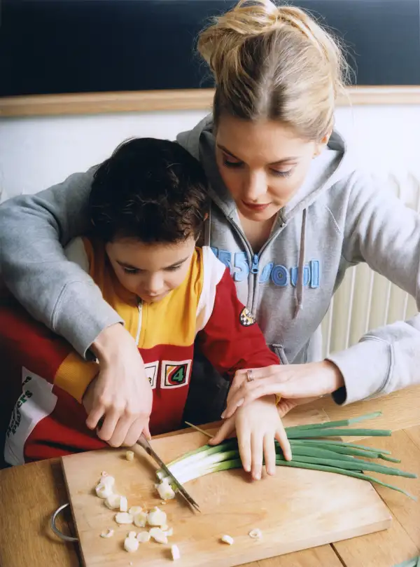 College student teaching child to cook.