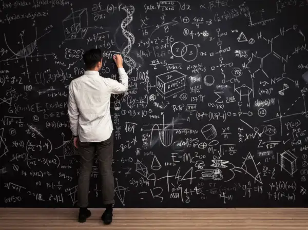Man writing formulas on a chalkboard