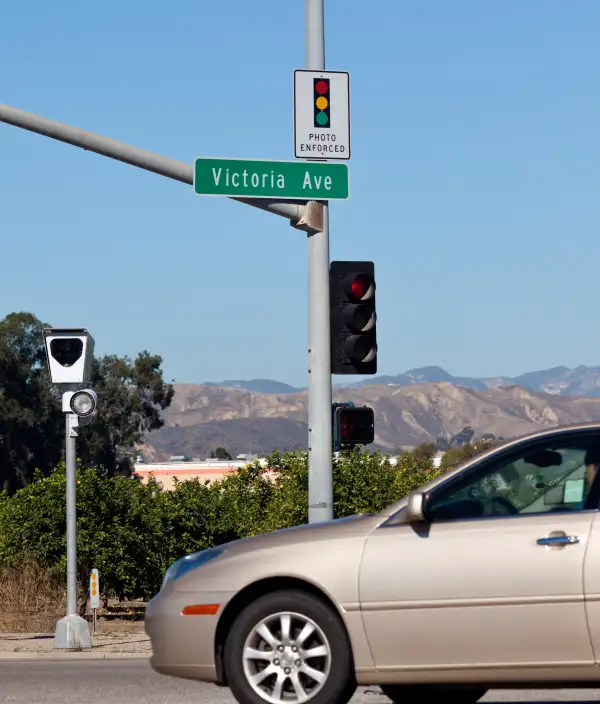 Car driving through intersection with photo enforced camera radar.