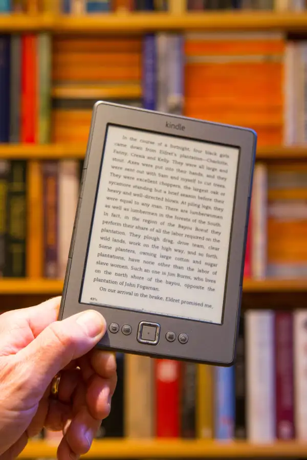 Amazon Kindle in front of a bookshelf