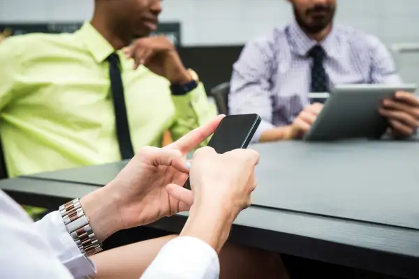 Man on smartphone in the middle of meeting