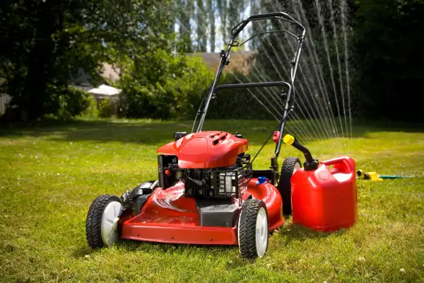 Red lawn mower and sprinkler on lawn