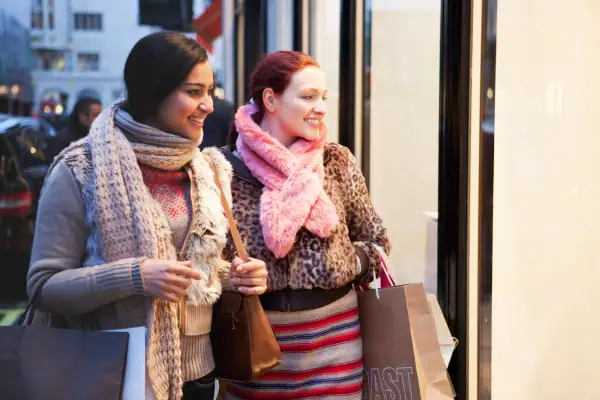 two women looking in shop windows at dusk