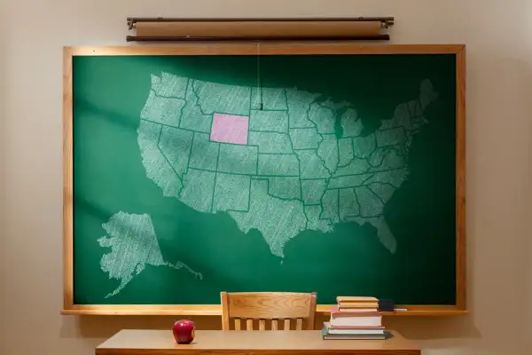 Classroom with map of United States on chalkboard. Wyoming is shaded pink.
