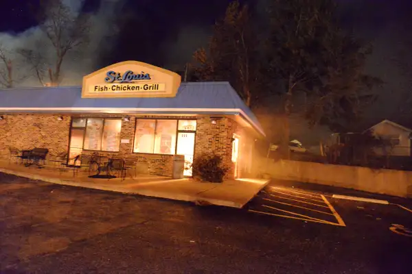 Flames illuminate the St. Louis Fish & Chicken Grill next door to where fire crews worked to douse a burning furniture store.