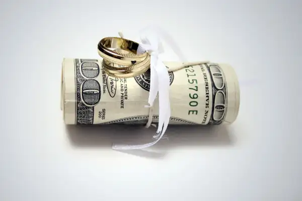 wedding rings tied to roll of $100 bills