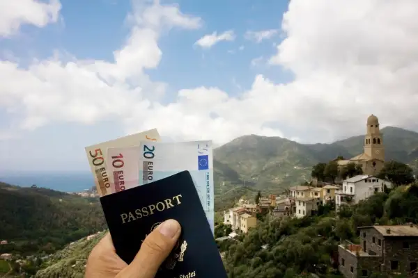 Passport and Euros in front of Italian landscape