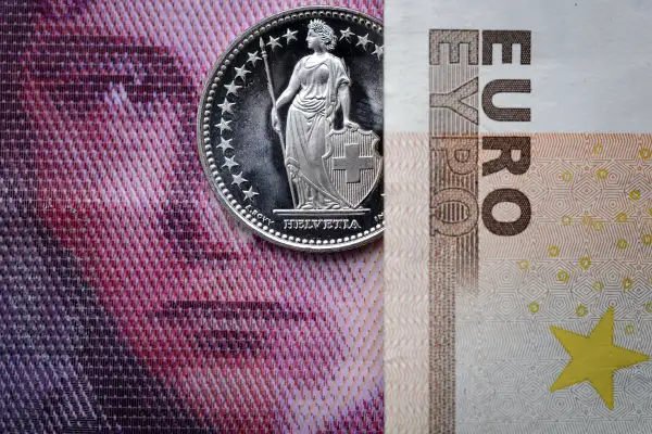 A Swiss coin is seen beneath a euro banknote on Januay 15, 2015 in Lausanne. In a shock announcement on January 15, Switzerland's central bank said it was ending a three-year bid to artificially hold down the value of the Swiss franc against the euro, in a move that immediately sent the safe haven currency soaring.