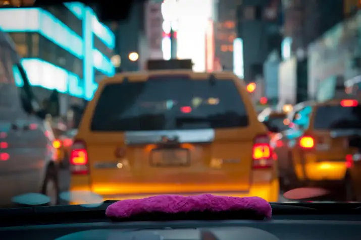 A pink mustache on the dashboard as Bouchaib El Hassani, 31, a Lyft driver, makes his way through midtown.