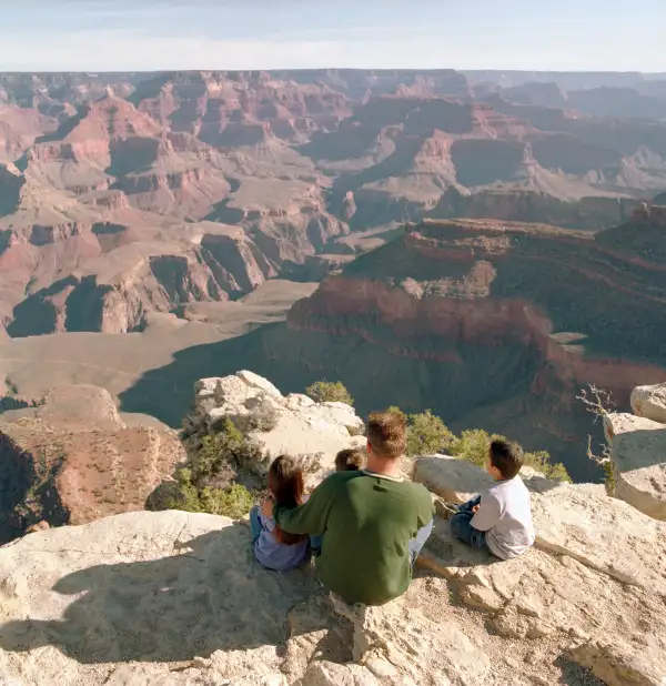 family sitting on the edge of the Grand Canyon