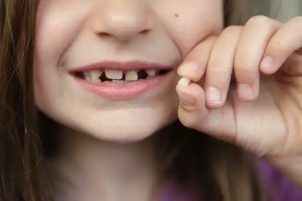 girl holding up tooth