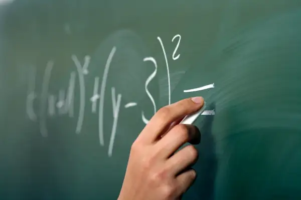 hand doing math equations on chalkboard