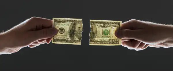 two hands pulling $100 bill and ripping it