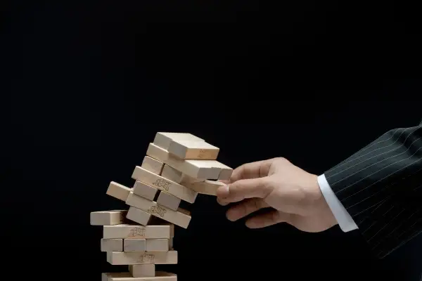 business person pulling piece out of jenga tower