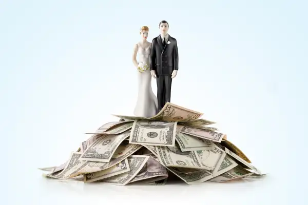 bride and groom wedding toppers on top of heap of cash
