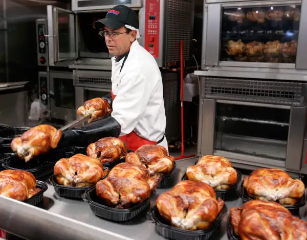 A Costco butcher spreads out roasted chicken at Costco in Mountain View, California.