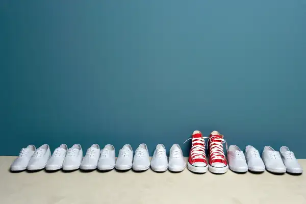 Pair of red Converse sneakers in row of white Keds sneakers