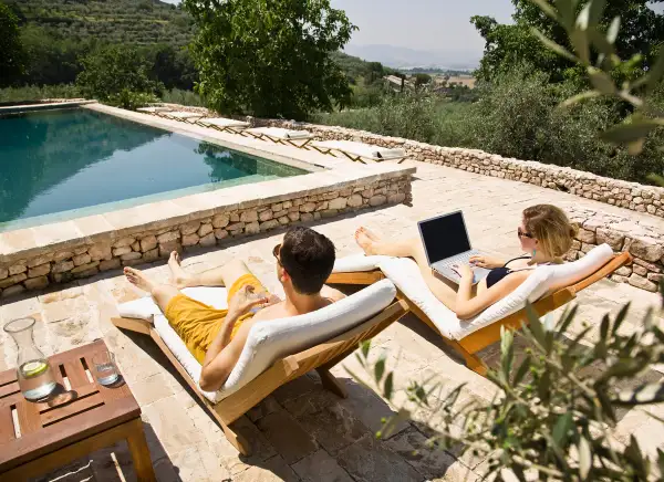 couple by the pool, woman on laptop