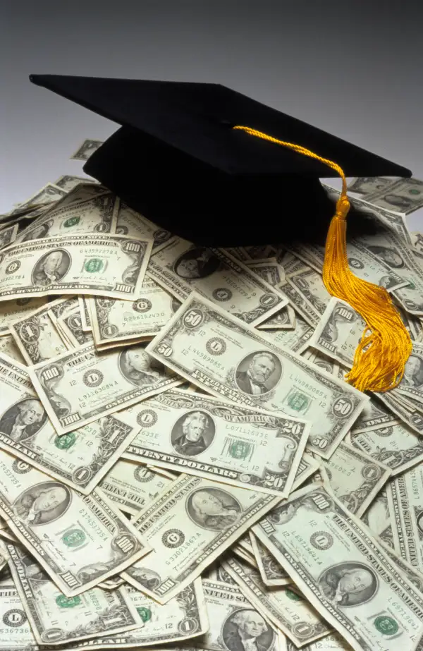 graduation cap mortarboard on top of pile of cash