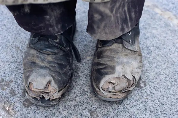 worn out dusty shoes with holes in them