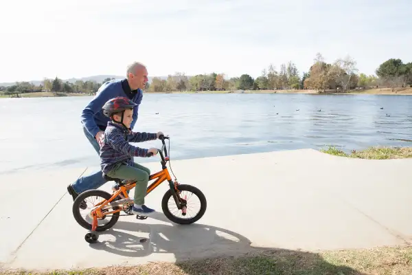 senior adult teaching child to ride bike