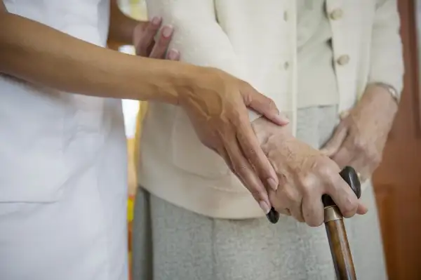 caregiver helping woman with cane