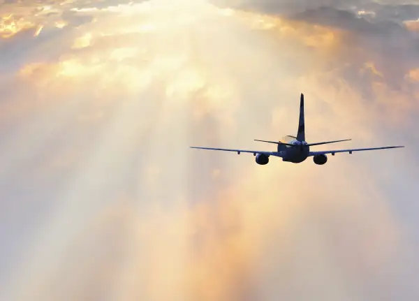 airplane flying off into the dawn with colorful clouds