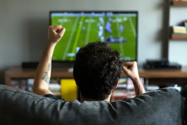 student on couch cheering at Football on TV