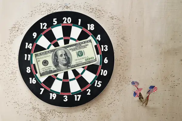 $100 bill on target and darts on wall