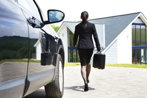 woman in business suit walking from car to house