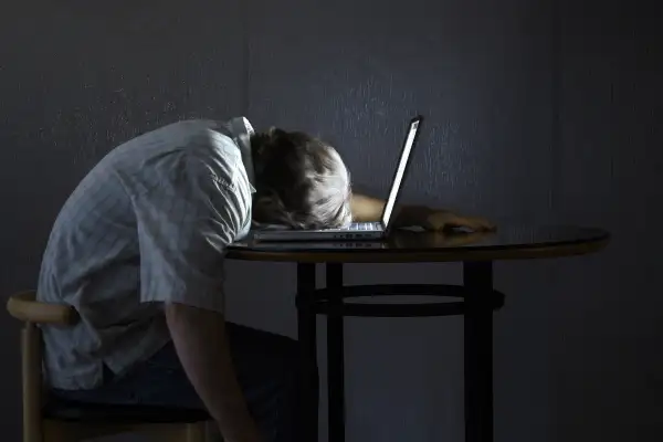 man asleep on laptop on table