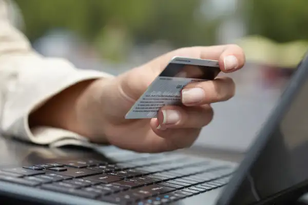 woman holding credit card and looking at laptop