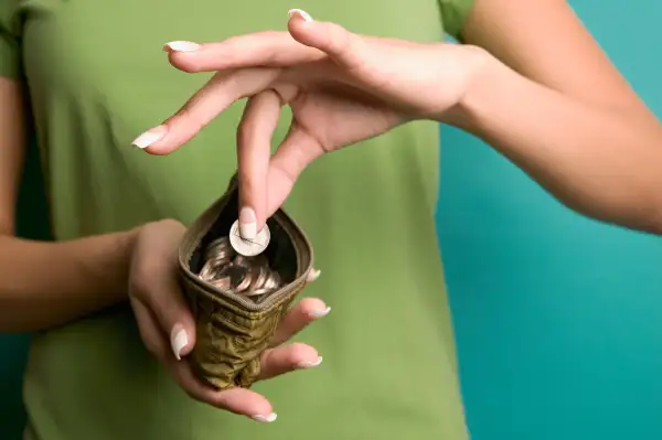 young woman putting coin in change purse