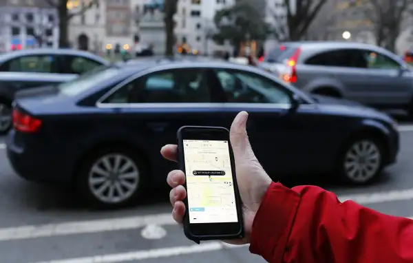 person using Uber app on mobile with car in background