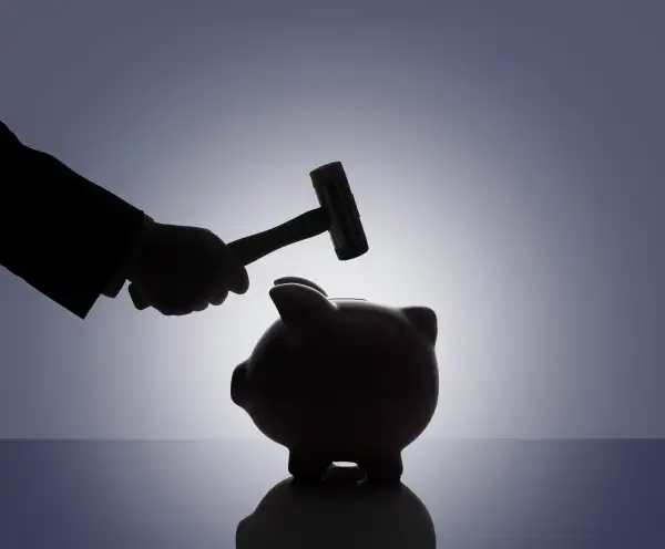 silhouette of hammer coming down on piggy bank