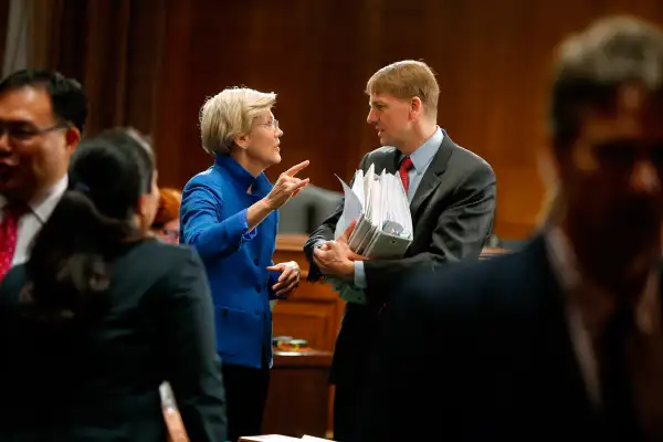 U.S. Senator Elizabeth Warren (D-MA) (L) talks with U.S. Consumer Financial Protection Bureau Director Richard Cordray (R) after he testified about Wall Street reform before a Senate Banking Committee hearing on Capitol Hill in Washington September 9, 2014.