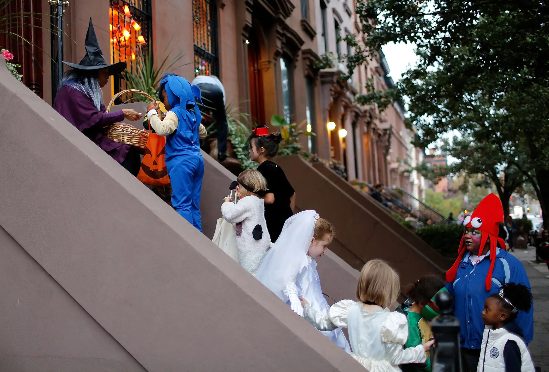 Linda Vital (L) passes out candy to halloween revelers as they stop at a private residence on Greene St. in Clinton Hill, Brooklyn to  Trick or Treat  in Clinton Hill, Brooklyn on October 31, 2013 in New York City.