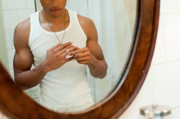 man removing wedding ring in bathroom