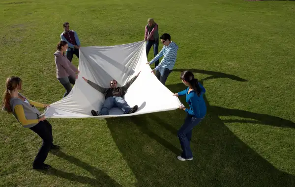 people catching a man in a sheet after a trust fall