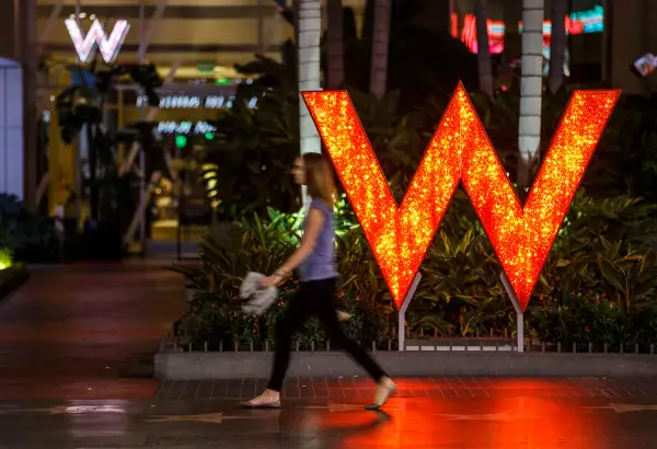 A woman walks past signage displayed outside of the W Hotel Hollywood in Hollywood, California, on October 26, 2015.