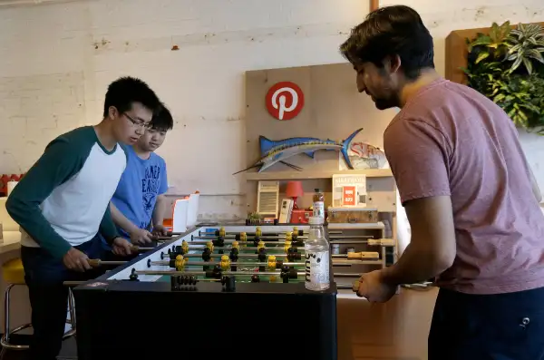 Pinterest software engineer interns Kevin Lau, from left, Charlie Gu and Neil Raina play foosball in the office in San Francisco, Wednesday, April 1, 2015. The San Francisco-based venture capital darling celebrated its fifth birthday in March 2015.