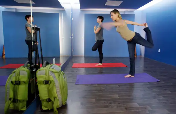 In this January 27, 2012 photo, travelers Maria Poole, right, and Lindsey Shepard, practice yoga at San Francisco International Airport's new Yoga Room, in San Francisco. The quiet, dimly lit studio officially opened last week in a former storage room just past the security checkpoint at SFO's Terminal 2. Airport officials believe the 150-square-foot room with mirrored walls is the world's first airport yoga studio, said spokesman Mike McCarron.