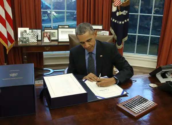 U.S. President Barack Obama signs the budget bill that will fund the government until next September, in the Oval Office at the White House December 18, 2015 in Washington, DC.