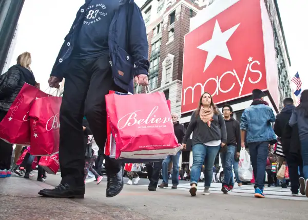 Shoppers carry bags as they cross a pedestrian walkway near Macy's in Herald Square, November 27, 2015, in New York.