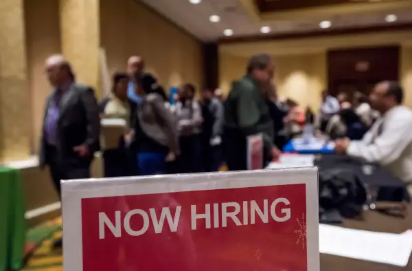 Now Hiring  signage is displayed as job seekers wait in line to enter the San Jose Career Fair in San Jose, California, on November 10, 2015.